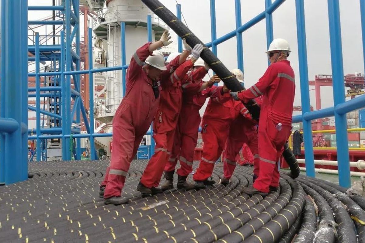 Crew handling flexible pipe on a carousel